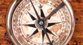 close up of the top view of an aged and weathered compass on a wooden background