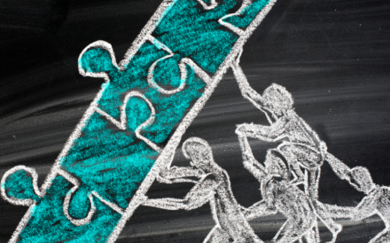 Chalk drawing of individuals lifting puzzle pieces.